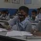 Sejumlah siswa mengenakan masker saat prose belajar mengajar di sebuah sekolah pemerintah di Hyderabad, India, Rabu (4/3/2020). Beberapa siswa memakai masker yang dibuat sendiri, dari kain maupun dari kertas. (AP Photo/Mahesh Kumar A.)
