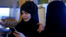 Seorang wanita berhijab memainkan ponselnya saat berada di sebuah kafe di Riyadh, Arab Saudi (6/10). (REUTERS/Faisal Al Nasser)