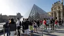 Pengunjung mengentre di piramida Louvre yang dirancang arsitek China Ieoh Ming Pei, pintu masuk ke Museum Louvre pada hari pertama pembukaan di Paris (6/7/2020). Setelah berbulan-bulan ditutup akibat lockdown Covid-19, Museum Louvre  kembali dibuka pada 6 Juli 2020. (AFP/Francois Guillot)