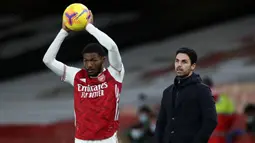 Gelandang Arsenal, Ainsley Maitland-Niles bersiap melakukan lemparan ke dalam di depan pelatih Mikel Arteta saat menghadapi Southampton dalam laga Liga Inggris 2020/2021 di Emirates Stadium, London (16/12/2020). Meski Ainsley Maitland-Niles telah dipromosikan ke tim utama Arsenal pada awal musim 2017/2018, nyatanya ia lebih banyak dipinjamkan ke beberapa klub. Kini ia tengah dipinjamkan ke Southampton sejak awal musim 2022/2023. (AFP/Pool/Peter Cziborra)