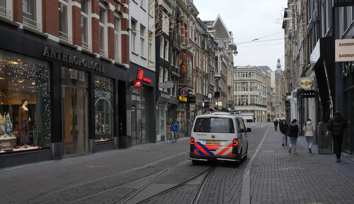 Polisi mengendarai mobil patroli mereka di jalan perbelanjaan yang biasanya ramai di pusat kota Amsterdam, 20 Desember 2021. Negara-negara di Eropa mempertimbangkan pembatasan yang lebih ketat guna membendung gelombang baru infeksi COVID-19 yang didorong oleh varian omicron.  (AP Photo/Peter Dejong)