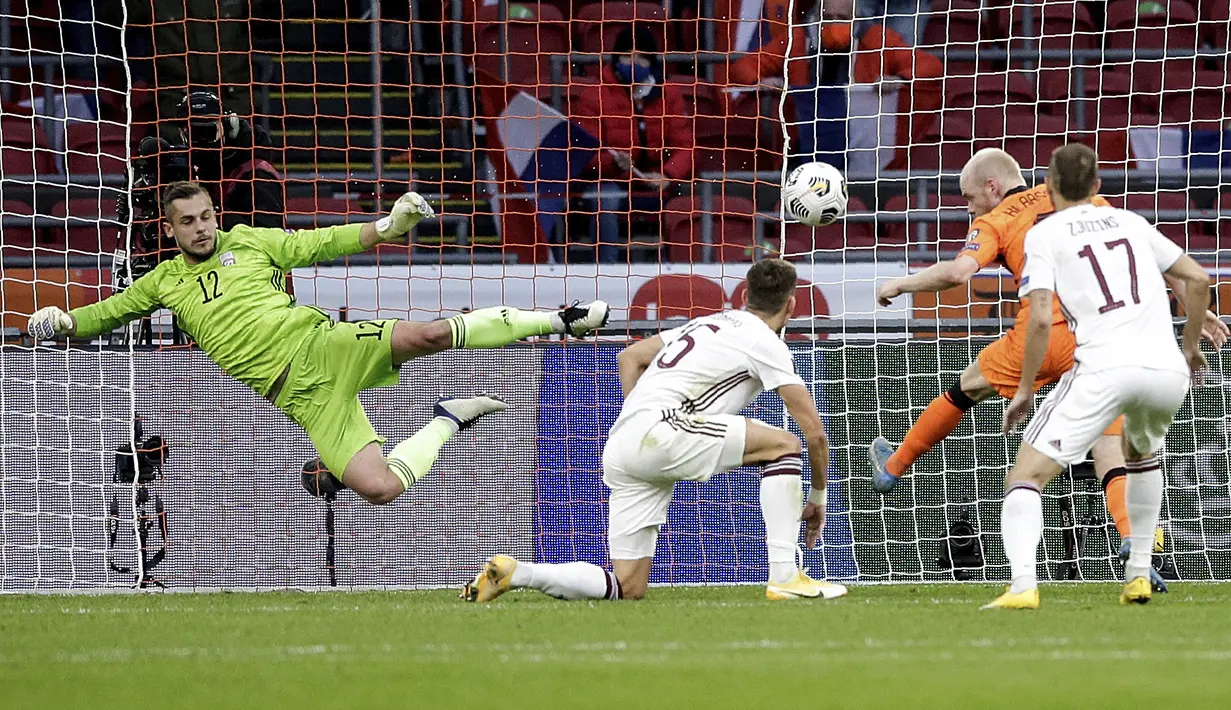 Kiper Latvia, Roberts Ozols menyelamatkan upaya mencetak gol pemain Belanda Davy Klaassen selama lanjutan Kualifikasi Piala Dunia 2022 zona Eropa Grup G di Johan Cruyff ArenA, Minggu (28/3/2021). Belanda sementara menguntit di posisi ketiga klasemen dengan tiga angka. (AP Photo/Peter Dejong)