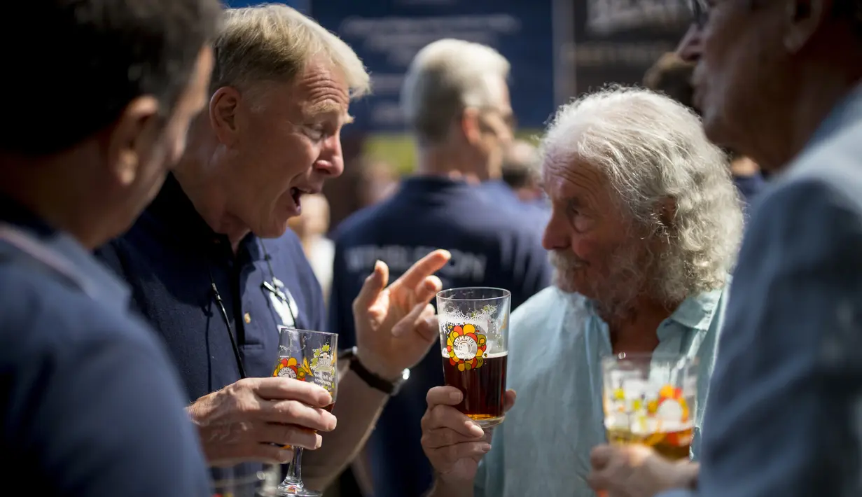 Sejumlah pria berbincang saat menikmati bir selama The Great British Beer Festival di London (6/8/2019). Great British Beer Festival, yang diselenggarakan CAMRA, menyediakan ratusan bir putih asli, bir internasional dan sari buah asli dan perries. (AFP Photo/Tolga Akmen)