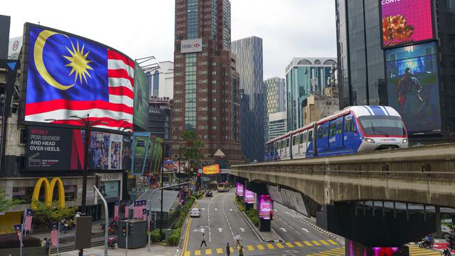 <span>Sebuah LRT (Light Rain Transit) melewati papan bendera Nasional di Kuala Lumpur, Malaysia, Selasa (14/9/2021). Malaysia pecah rekor tembus dua juta kasus Covid-19 dengan tambahan 15.669 kasus Selasa (14/9/2021). (AP Photo/Vincent Thian)</span>