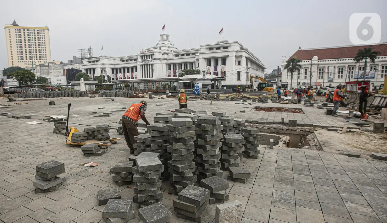 Pekerja menyelesaikan proyek revitalisasi di depan Stasiun Jakarta Kota, kawasan Kota Tua, Jakarta, Sabtu (23/7/2022). Pemprov DKI Jakarta menyatakan program revitalisasi di kawasan Kota Tua salah satunya bertujuan untuk meningkatkan aksesibilitas dengan mengintegrasikan beragam moda transportasi seperti kereta api, MRT, Transjakarta hingga angkutan perkotaan. (Liputan6.com/Faizal Fanani)