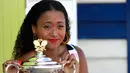 Petenis Jepang Naomi Osaka menunjukkan trofi Australia Terbuka 2019 di Pantai Brighton Melbourne, Australia, Minggu (27/1). Osaka bakal dinobatkan sebagai petenis putri peringkat satu dunia karena menjuarai dua turnamen Grand Slam. (AP Photo/Aaron Favila)