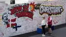 Orang-orang membaca harapan baik pada mural untuk gelandang timnas Denmark Christian Eriksen di dinding fanzone di Kopenhagen, Senin (14/6/2021). Eriksen mengalami serangan jantung dan sempat tak sadarkan diri saat memperkuat timnas Denmark vs Finlandia di Euro 2020. (AP Photo/Martin Meissner)