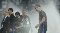 Hector Fort (kanan) sengaja membasahi tubuhnya dengan air dari sprinkler atau alat pemancar air sebagai wujud suka cita setelah Barcelona memastikan gelar juara Liga Spanyol di kandang Espanyol, Jumat (16/5/2025) dini hari WIB. (AP Photo/Joan Monfort)