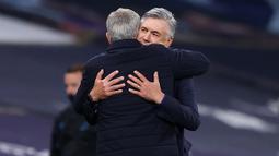 Pelatih Tottenham Hotspur, Jose Mourinho, berpelukan dengan pelatih Everton, Carlo Ancelotti, pada laga Premier League, Senin (6/7/2020). Mourinho melanggar aturan jarak sosial demi memeluk Carlo Ancelotti. (AFP/Richard Heathcote)