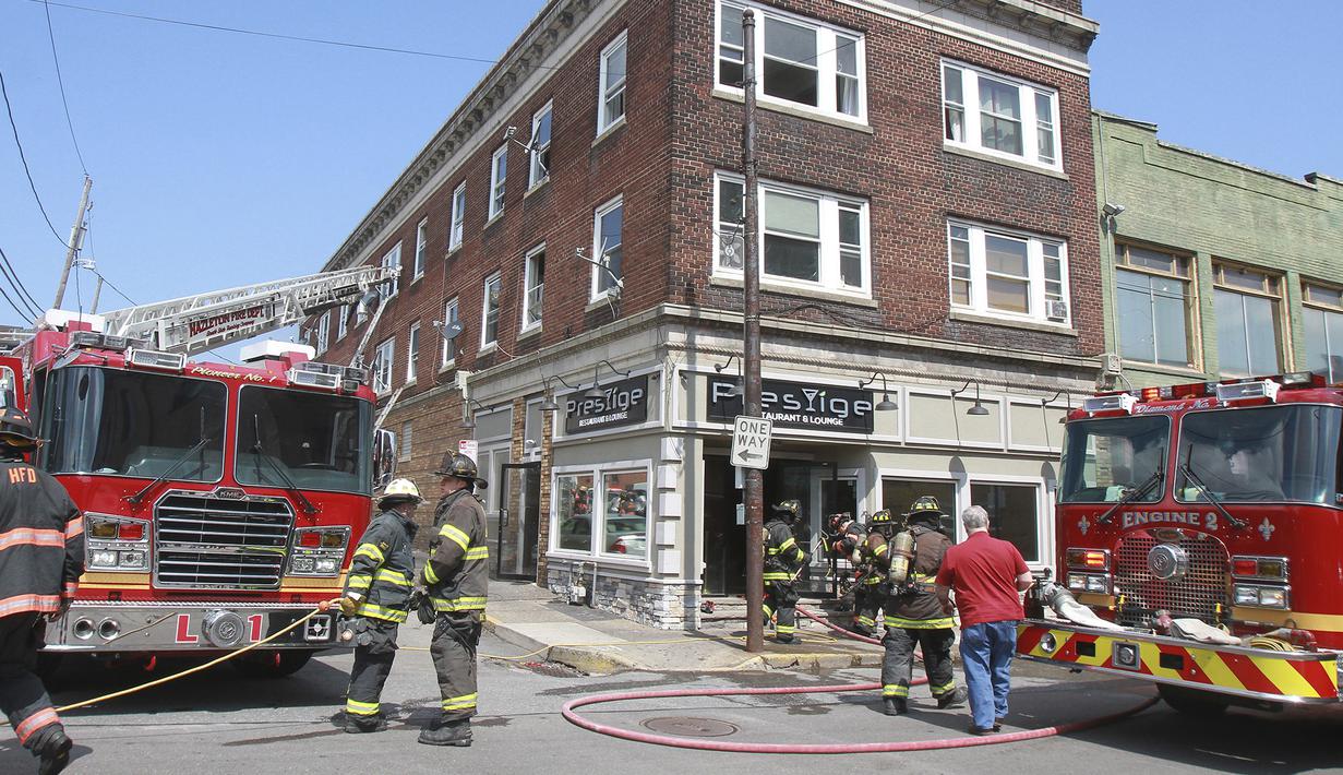 Petugas pemadam kebakaran berdiri di lokasi kebakaran di Hazleton, Pennsylvania (26/7/2019). Restoran dan apartemen Prestigio rusak dilalap api. (Warren Ruda/Hazleton Standard-Speaker via AP)