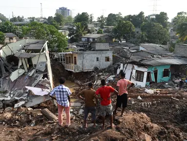 Warga Sri Lanka mengamati rumah mereka yang rusak tertimbun gundukan sampah yang longsor di Meetotamulla, dekat ibukota Kolombo, Minggu (16/4). Sedikitnya 23 orang tewas akibat tanah longsor di tempat pembuangan sampah tersebut. (ISHARA S. KODIKARA/AFP)