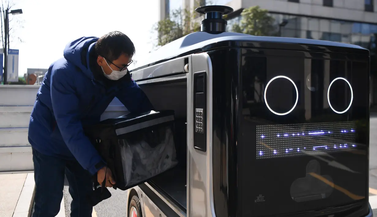 Seorang staf meletakkan makanan ke dalam robot pengiriman di Changsha, Provinsi Hunan, China tengah, pada 14 Februari 2020. Dua robot pengiriman dialihfungsikan untuk mengantar makan siang dan makan malam bagi para karyawan di perusahaan yang melanjutkan produksi di kawasan itu. (Xinhua/Xue Yuge)
