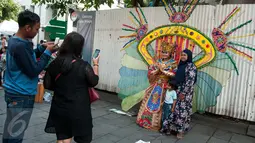 Warga berpose dengan seniman yang mencari nafkah di kawasan Kota Tua, Jakarta, Senin (5/1). Kota Tua masih menjadi tempat pilihan untuk warga Jakarta dan sekitarnya mengisi waktu libur. (Liputan6.com/Gempur M Surya)