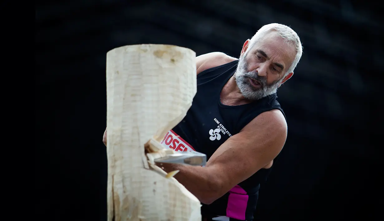 Patxi Larretxea memotong batang pohon menggunakan kapak pada hari ketiga festival San Fermin di Pamplona, Spanyol, Senin (8/7/2019). Festival San Fermin menghadirkan beberapa olahraga pedesaan Basque seperti menggergaji dan memotong pohon dengan kapak. (JAIME REINA/AFP)