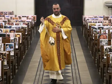 Pastor Katolik Georges Nicoli merayakan misa Kamis Putih disiarkan langsung di Facebook, dengan foto-foto jemaat yang ditempel dibangku di gereja Notre Dame De Lourdes di Bastia, di pulau Korsika Mediterania, Prancis (9/4/2020). (AFP/Pascal Pochard-Casabianca)