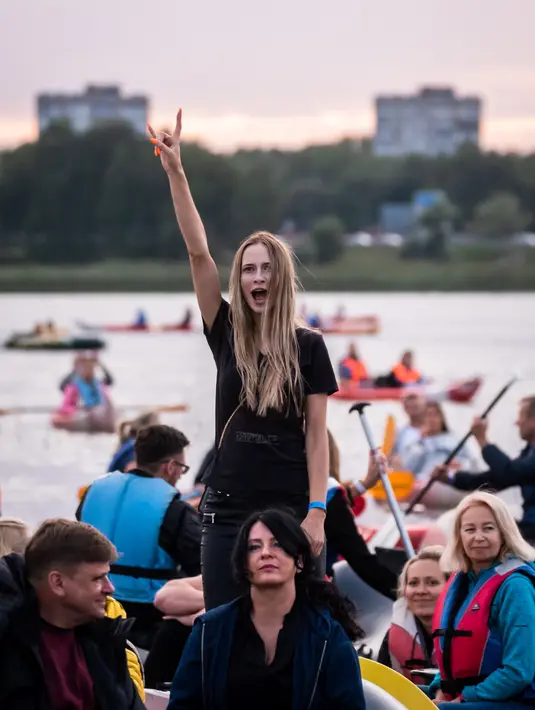Para penonton menikmati konser musik Laivā dari atas perahu di Danau Juglas, Riga, Latvia, 14 Agustus 2021. Warga Latvia bisa menikmati konser musik dari atas kayak, sampan, dan kapal motor bahkan ketika mereka belum divaksin COVID-19. (Gints Ivuskans/AFP)