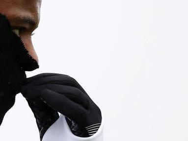Bek Juventus, Patrice Evra, menutupi hidungnya karena dingin saat latihan jelang laga Liga Champions melawan Sevilla di Vinovo, Italia, Senin (21/11/2016). Cuaca dingin mewarnai latihan Juventus. (AFP/Marco Bertorello)
