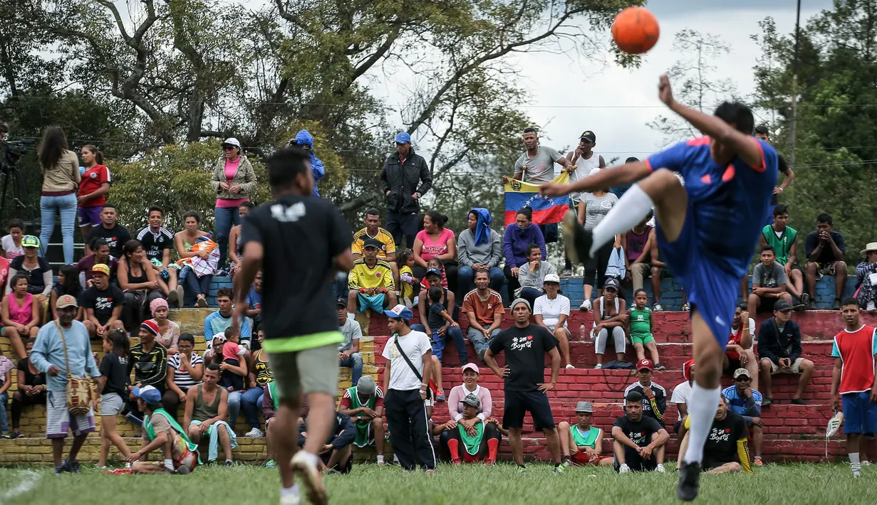 Para migran Venezuela bermain sepak bola di kamp sementara di Bogota, Kolombia (21/11). Pejabat kota menyelenggarakan turnamen sepak bola bagi migran yang tinggal di kamp yang dibangun badan kesejahteraan sosial kota tersebut. (AP Photo/Ivan Valencia)