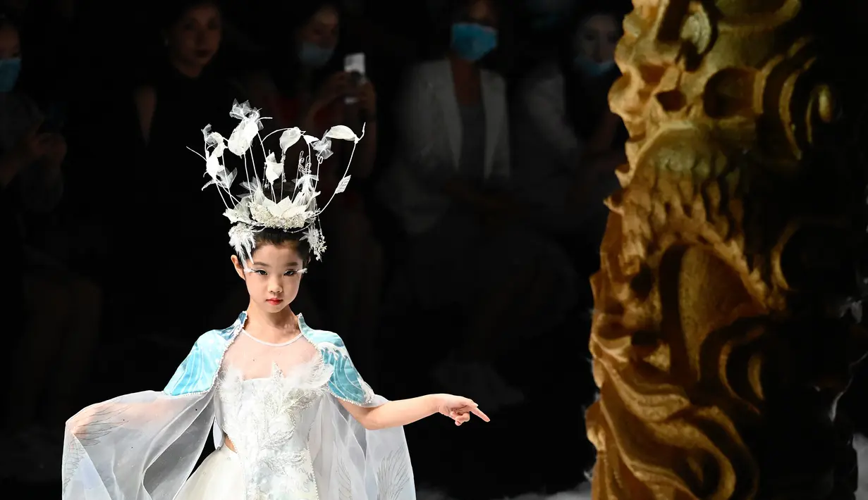 Seorang model cilik menampilkan kreasi dari koleksi Jinshangyuyi karya desainer Wang Cong selama China Fashion Week di Beijing pada Kamis (9/9/2021). Gelaran pekan mode tersebut tetap digelar di tengah pandemi corona covid-19. (Giok GAO / AFP)
