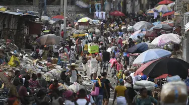 Seorang perempuan membawa baskom dengan barang-barangnya di pasar Petion-Ville di Port-au-Prince, empat hari setelah pembunuhan Presiden Haiti Jovenel Moise, Minggu (11/7/2021). Moïse tewas dibunuh dalam serangan di kediaman pribadinya, pada Rabu 7 Juli 2021 dini hari. (AP Photo/Matias Delacroix)