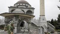 Seorang prajurit milisi Republik Rakyat Donetsk berjalan melewati masjid yang rusak akibat pertempuran sengit di daerah yang dikendalikan oleh pasukan separatis yang didukung Rusia di Mariupol, Ukraina, Selasa (19/4/2022).  (AP Photo/Alexei Alexandrov)