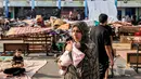 <p>Seorang wanita berjalan sambil menggendong bayi di taman bermain di sebuah sekolah yang dikelola oleh Badan Bantuan dan Pekerjaan PBB untuk Pengungsi Palestina (UNRWA) yang telah diubah menjadi tempat penampungan bagi para pengungsi Palestina di Khan Yunis di Jalur Gaza selatan pada 25 Oktober 2023. (Mahmud HAMS/AFP)</p>
