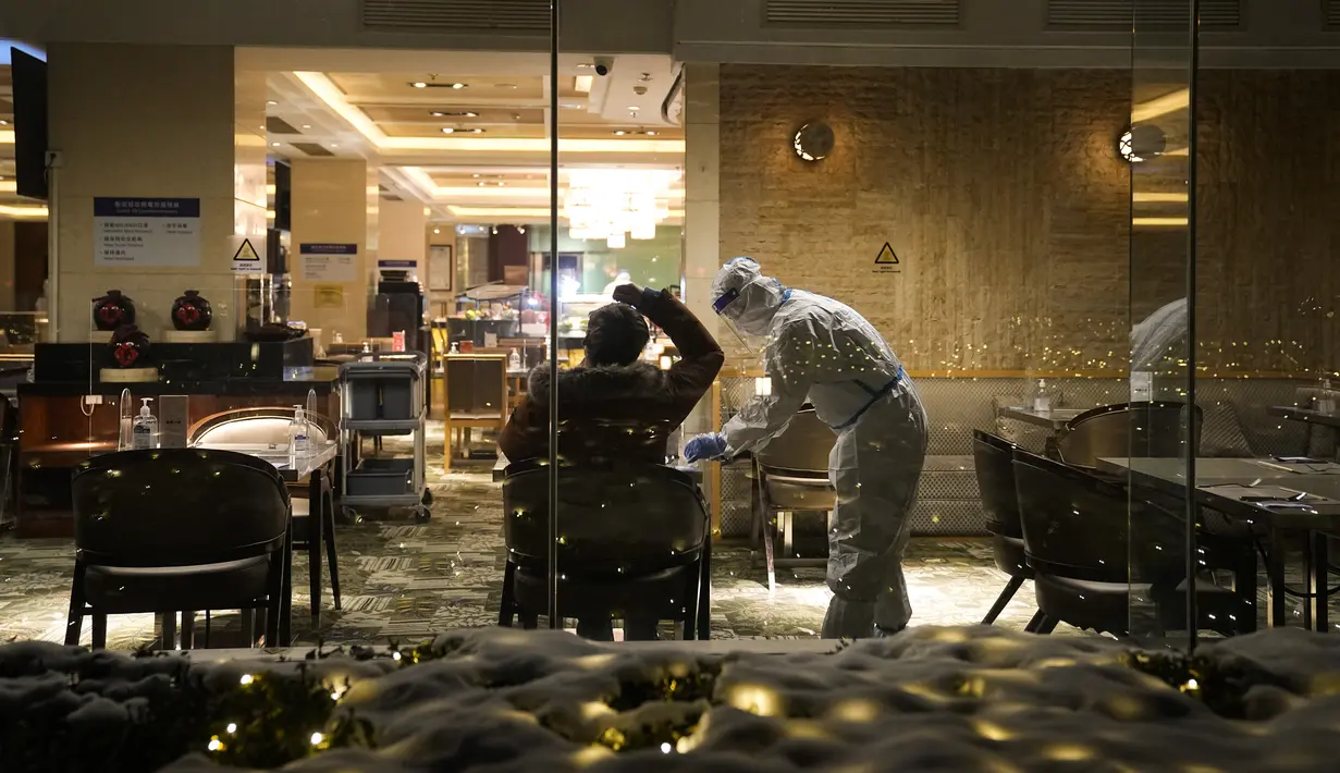 Seorang tamu mengenakan maskernya saat seorang pramusaji yang mengenakan pakaian pelindung diri atau hazmat menyerahkan tanda terima kepadanya di sebuah restoran di dalam Hotel Shangri-La pada Olimpiade Musim Dingin 2022, 16 Februari 2022, di Beijing. (AP Photo/Jae C.Hong)