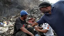 Seorang pemulung dihibur rekan-rekannya dan petugas pemadam kebakaran setelah sepupunya meninggal tertimpa longsoran ribuan kubik sampah di Tempat Pembuangan Akhir (TPA)  di Guatemala City, Guatemala, Rabu (27/4). (REUTERS/Josue Decavele)