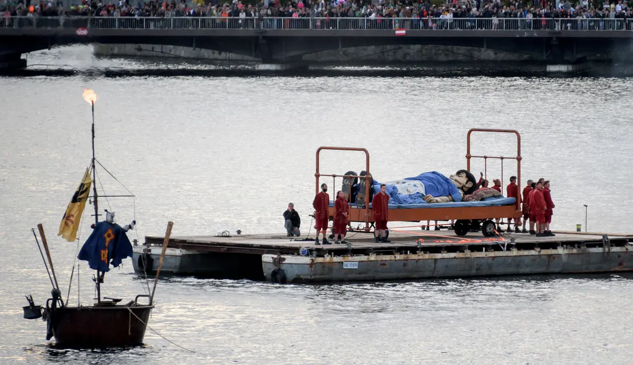 Boneka raksasa yang berbentuk seorang gadis kecil setinggi 5,5 meter terbaring di tempat tidur di Danau Jenewa, Swiss (1/10). (AFP Photo/Fabrice Coffrini)