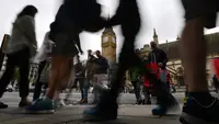 Pejalan kaki melintas di sekitar menara jam Big Ben yang mulai membisu di Elizabeth Tower, London, Senin (21/8). Membisunya Big Ben kali ini merupakan yang pertama kali setelah terakhir kali terjadi pada 157 tahun yang lalu. (BEN STANSALL / AFP)