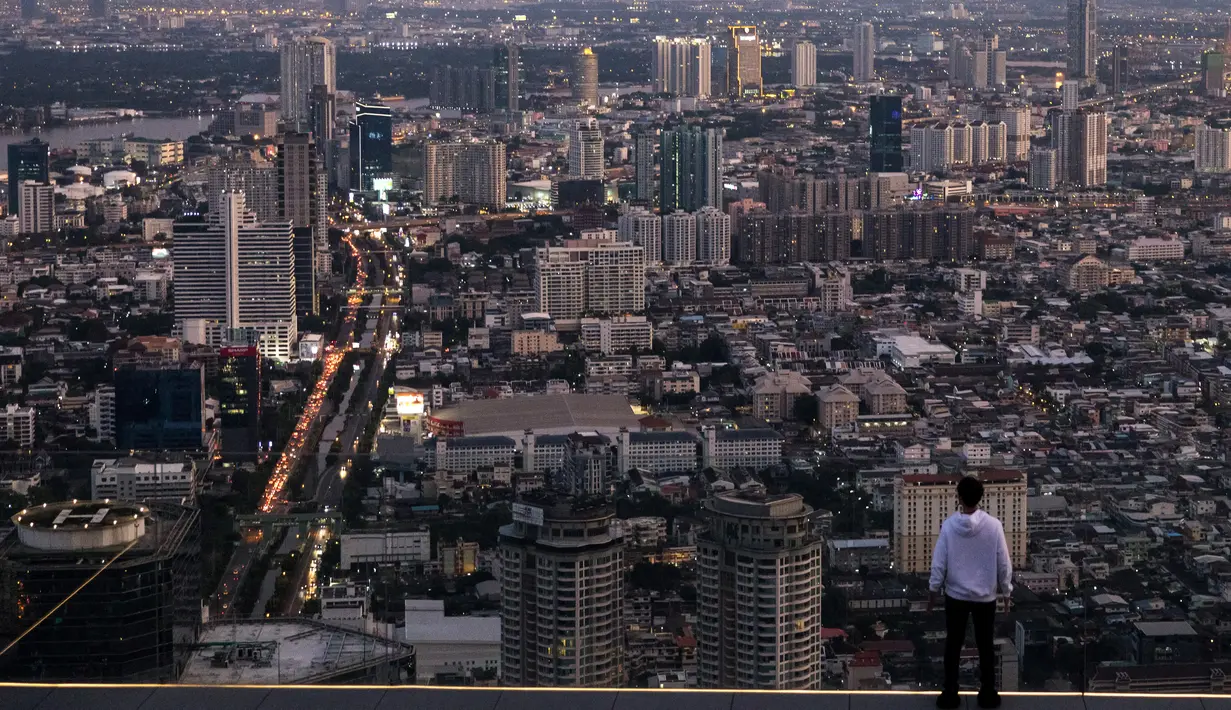 Seorang pria melihat ke cakrawala Cakrawala Bangkok dari dek observasi pencakar langit King Power Mahanakhon saat matahari terbenam pada 25 Oktober 2021. Dari ketinggian 314 meter, para pengunjung dapat melihat pemandangan ibu kota Thailand. (Jack TAYLOR / AFP)