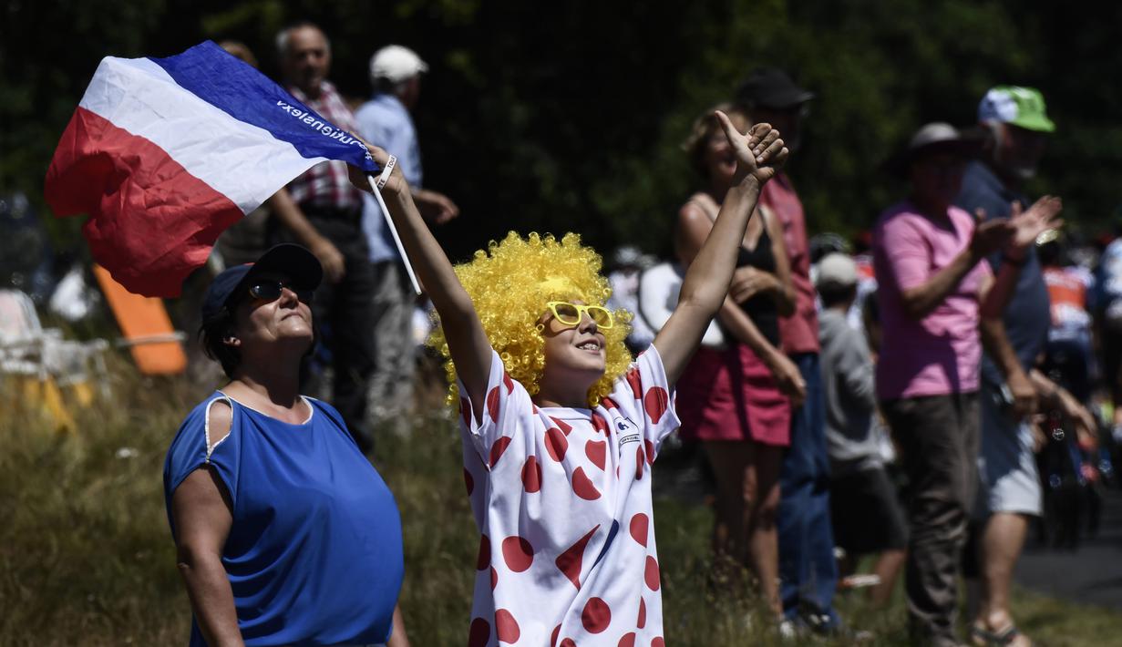 Aksi suporter memegang bendera Prancis saat menonton balapan  Tour de France pada etape ke-16 dengan jarak 165 km dari Le Puy-en-Velay dan Romans-sur-Isere, (18/7/2017).  (AFP/Jeff Pachoud)