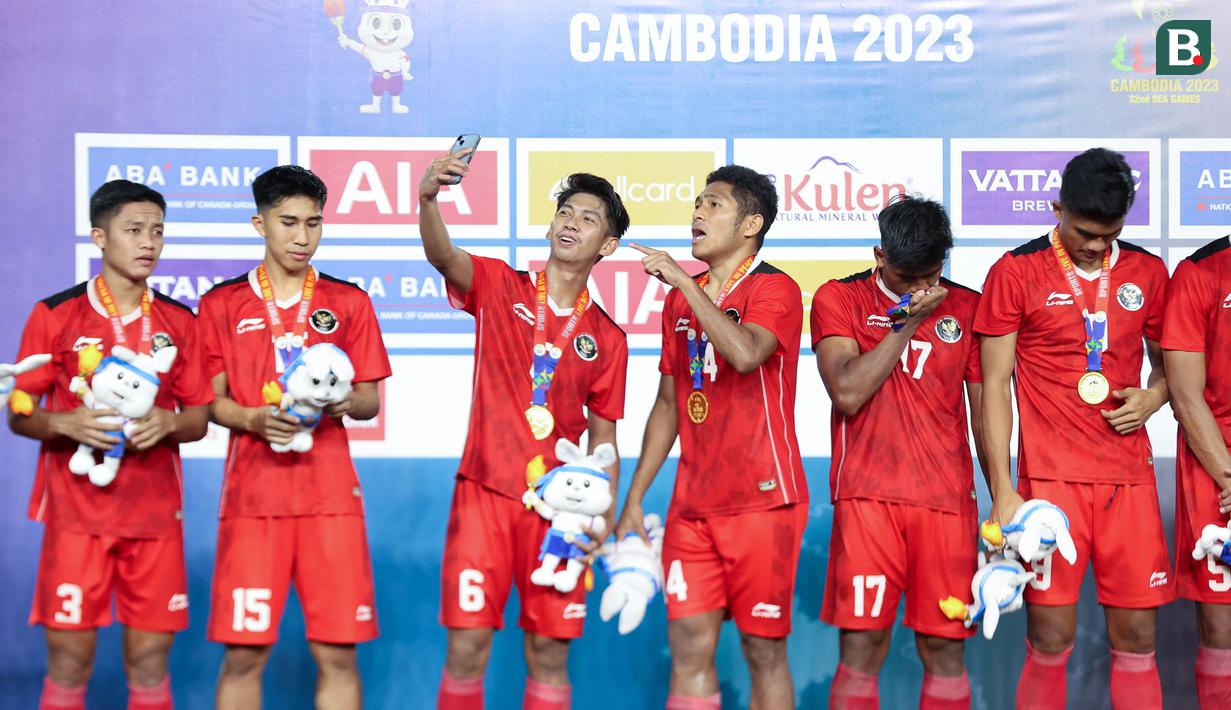 Pemain Timnas Indonesia U-22, Ananda Raehan (tengah kiri) bersama Fajar Fathur Rahman (tengah kanan) tengah mengabadikan momen menggunakan gawai saat penyerahan medali SEA Games 2023 di Olympic Stadium, Phnom Penh, Kamboja, Selasa (16/05/2023). (Bola.com/Abdul Aziz)