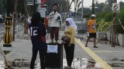Warga berfoto-foto di kawasan pedestrian Kali Besar, Kota Tua, Jakarta, Rabu (11/7). Masyarakat sudah bisa mengakses area yang proyek revitalisasinya telah berlangsung sejak 2017 lalu, dan menghabiskan anggaran Rp 260 miliar. (Liputan6.com/Arya Manggala)
