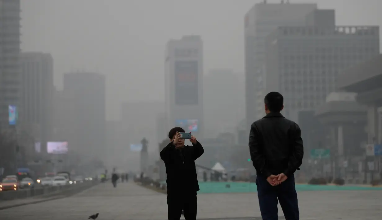 Warga mengambil foto di pusat kota Seoul, Korea Selatan, Selasa (5/3). Kementerian Lingkungan Korea Selatan mengeluarkan langkah-langkah pengurangan debu halus darurat pada hari Selasa. (AP Photo/Lee Jin-man)