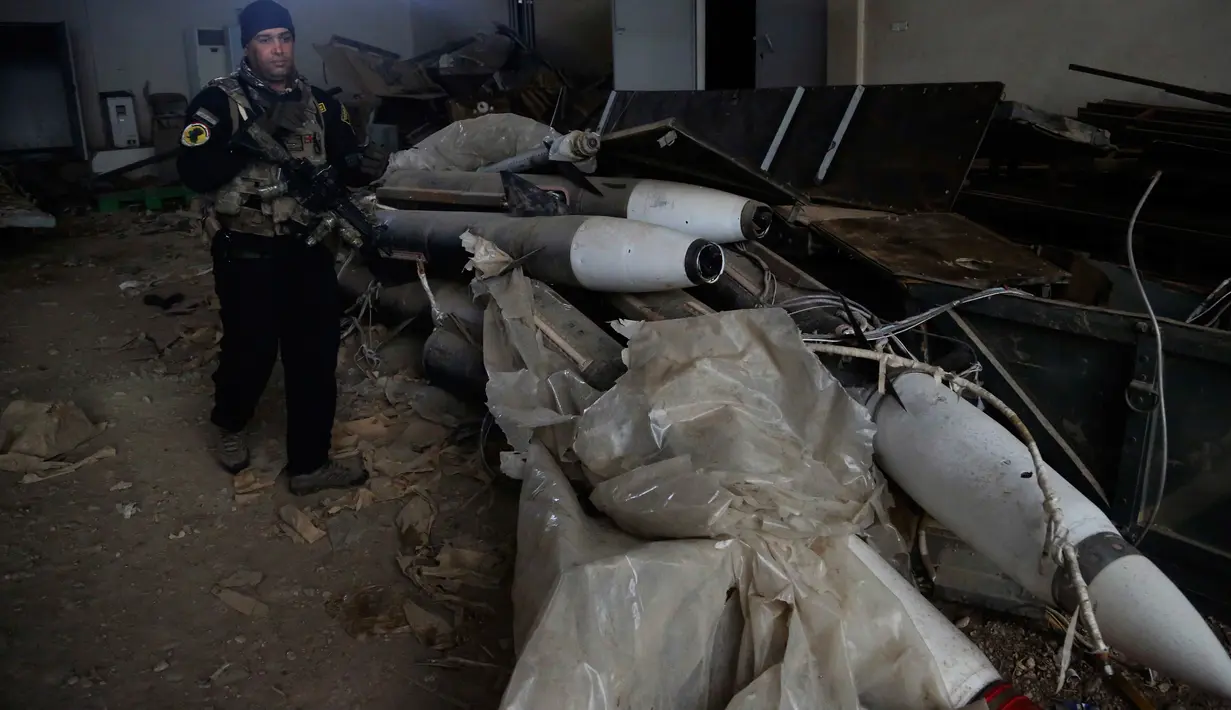 Pasukan khusus Irak berjalan dekat rudal yang ditemukan di sebuah gudang senjata milik ISIS di sisi timur Mosul, Sabtu (28/1). Senjata-senjata yang ditemukan di antara puluhan roket yang tersembunyi di unit penyimpanan di kota. (AP Photo/Khalid Mohammed)