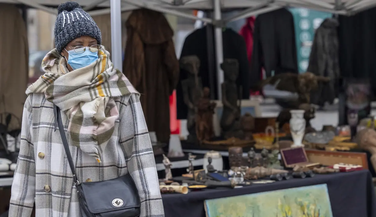 Seorang perempuan mengenakan masker saat mengunjungi pasar loak Marrolles di Brussels, Rabu (17/11/2021). Pemerintah Belgia mewajibkan kembali penggunaan masker dan memberlakukan warga bekerja dari rumah dalam upaya untuk menahan lonjakan baru kasus COVID-19. (AP Photo/Olivier Matthys)