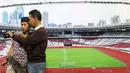 Pengunjung melihat hasil foto berlatar Stadion Utama Gelora Bung Karno yang dipamerkan di area Stadion GBK, Jakarta, Rabu (29/8). Sejumlah dokumentasi pembangunan stadion dicetak dan bisa dilihat warga. (Liputan6.com/Helmi Fithriansyah)