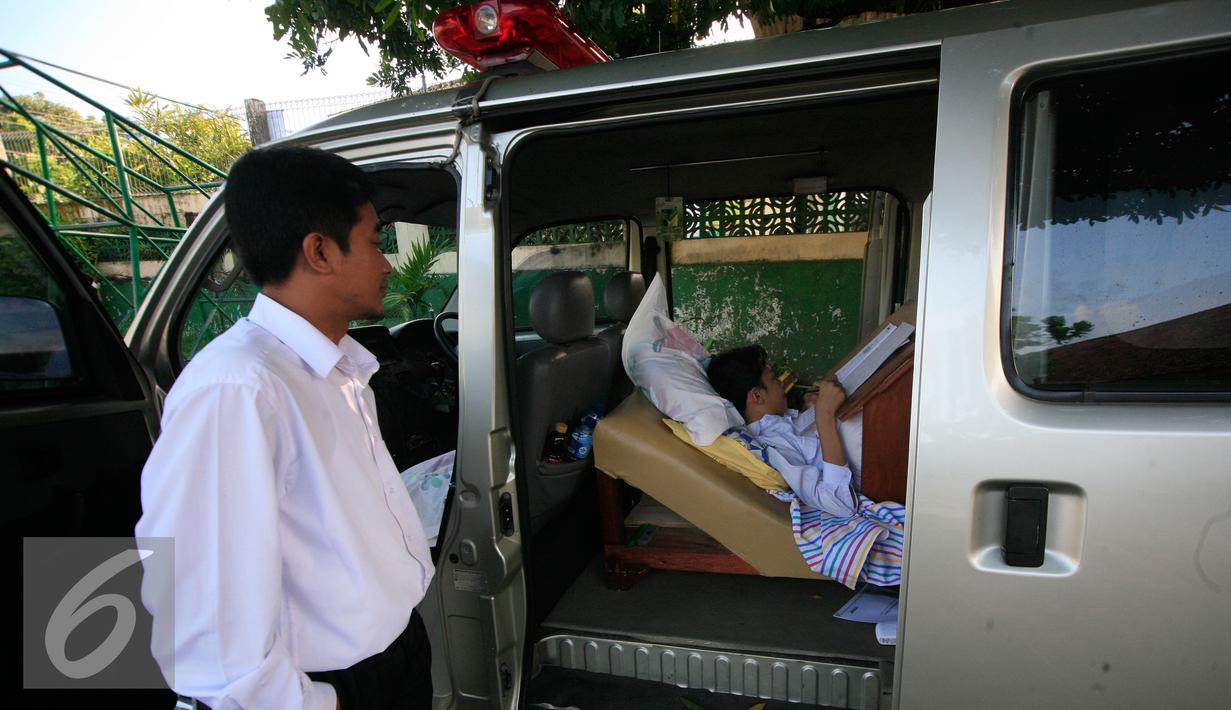 Petugas mengawasi siswa SMP N 2 Pakem ,Fitrian saat mengerjakan soal Ujian Nasional di halaman SMP N 2 Pakem, Sleman, (10/5). Akibat kecelakaan,Fitrian terpaksa melaksanakan UN di dalam mobil ambulans . (Liputan6.com/Boy Harjanto)