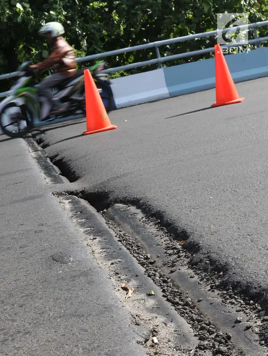 Pengendara melintasi salah satu ruas jalan layang yang retak di kawasan Kemayoran, Jakarta, Kamis (3/1). Akibat retakan ini, para pengendara harus lebih berhati-hati saat melintas. (Liputan6.com/Helmi Fithriansyah)
