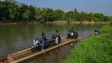 Warga bersama sepeda motornya menyeberangi Sungai Cisadane menggunakan rakit bambu di kawasan Ciseeng, Kabupaten Bogor, Jawa Barat, Kamis (11/6/2026). (merdeka.com/Arie Basuki)