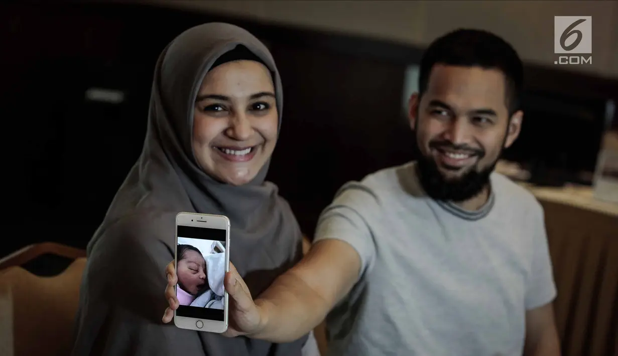 Teuku Wisnu bersama istrinya Shireen Sungkar menunjukkan foto anak ketiganya saat jumpa pers di RS Pondok Indah, Jakarta, Kamis (19/4). Anak ketiga Shireen dan Wisnu ini berjenis kelamin perempuan. (Liputan6.com/Faizal Fanani)