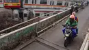 Tumpukan sarana transportasi umum itu terlihat jelas dari jembatan Jalan Terusan Dipo. Tampak dalam foto, warga melintas di jalan layang dekat Depo Kereta Rel Listrik (KRL) di Jalan Kampung Rawageni, Cipayung, Kota Depok, Jawa Barat, Selasa (20/01/2026). (Merdeka.com/Arie Basuki)