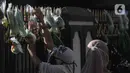 Warga mengambil berbagai sayuran yang digantung pada pagar rumah di Gang Palautan, Cilodong, Depok, Jawa Barat, Jumat (21/1/2022). Berbagi sayuran, beras, dan bumbu masak setiap Jumat ini bentuk solidaritas kepada warga lainnya yang terdampak pandemi COVID-19. (Liputan6.com/Herman Zakharia)