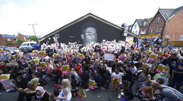 Pengunjuk Rasa  berlutut selama protes anti-rasisme di dekat mural striker Inggris Marcus Rashford, di dinding Coffee House Cafe di Copson Street, di Withington, Manchester, Inggris, Selasa (13/7/2021). Mural itu dicoret dengan coretan rasis setelah Inggris kalah dari Italia. (AP Photo/Jon Super)