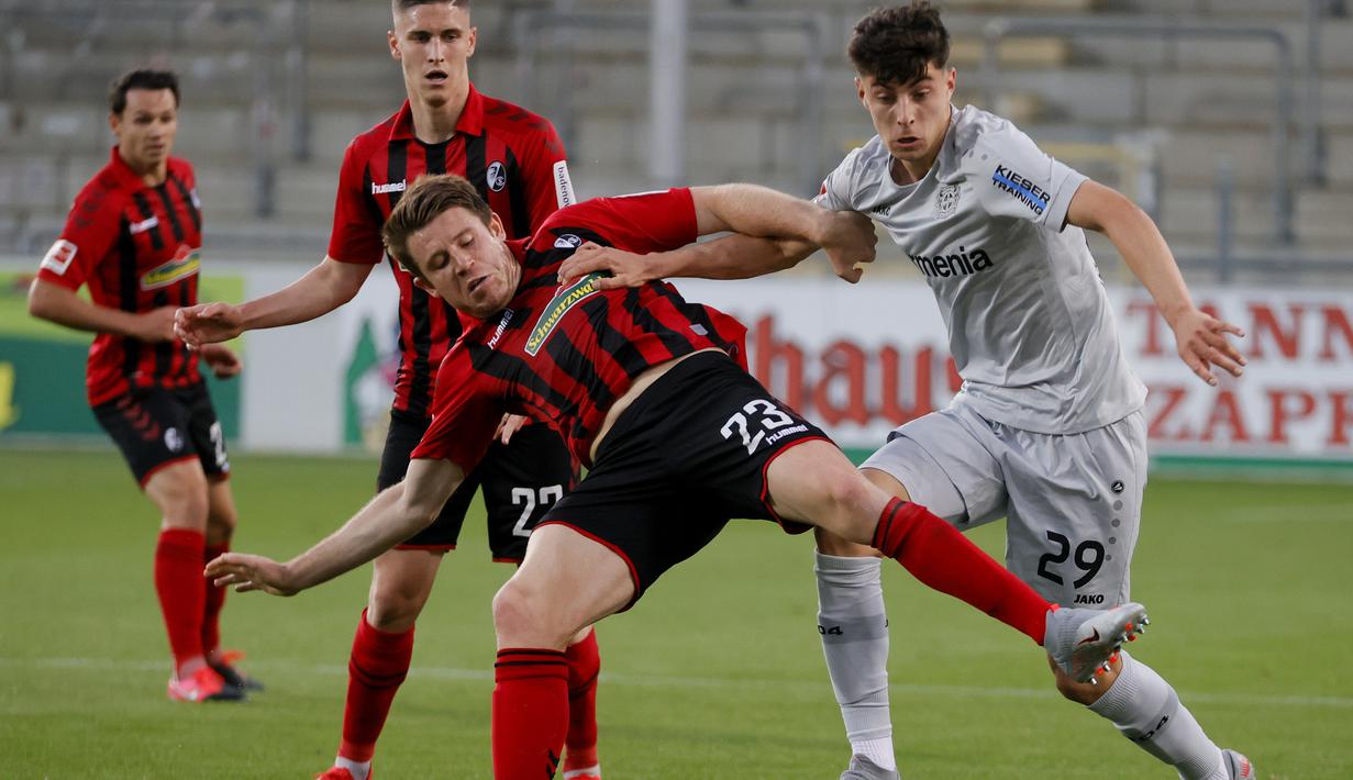 Gelandang Bayer Leverkusen, Kai Havertz, berebut bola dengan pemain Freigurg pada laga pekan ke-29 Bundesliga 2019/20 di Schwarzwald-Stadion, Sabtu (30/5/2020) dini hari WIB. Leverkusen menang 1-0 atas Freiburg. (AFP/Ronald Wittek/pool)