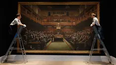 Petugas mengamati lukisan seniman jalanan Banksy yang dipajang di ruang lelang Sotheby, London, Jumat (27/9/2019). Lukisan Banksy 'Devolved Parliament' itu bakal dilelang yang diperkirakan bernilai 1,5-2 juta poundsterling (Rp25-35,1 miliar) pada Oktober mendatang. (AP/Kirsty Wigglesworth)