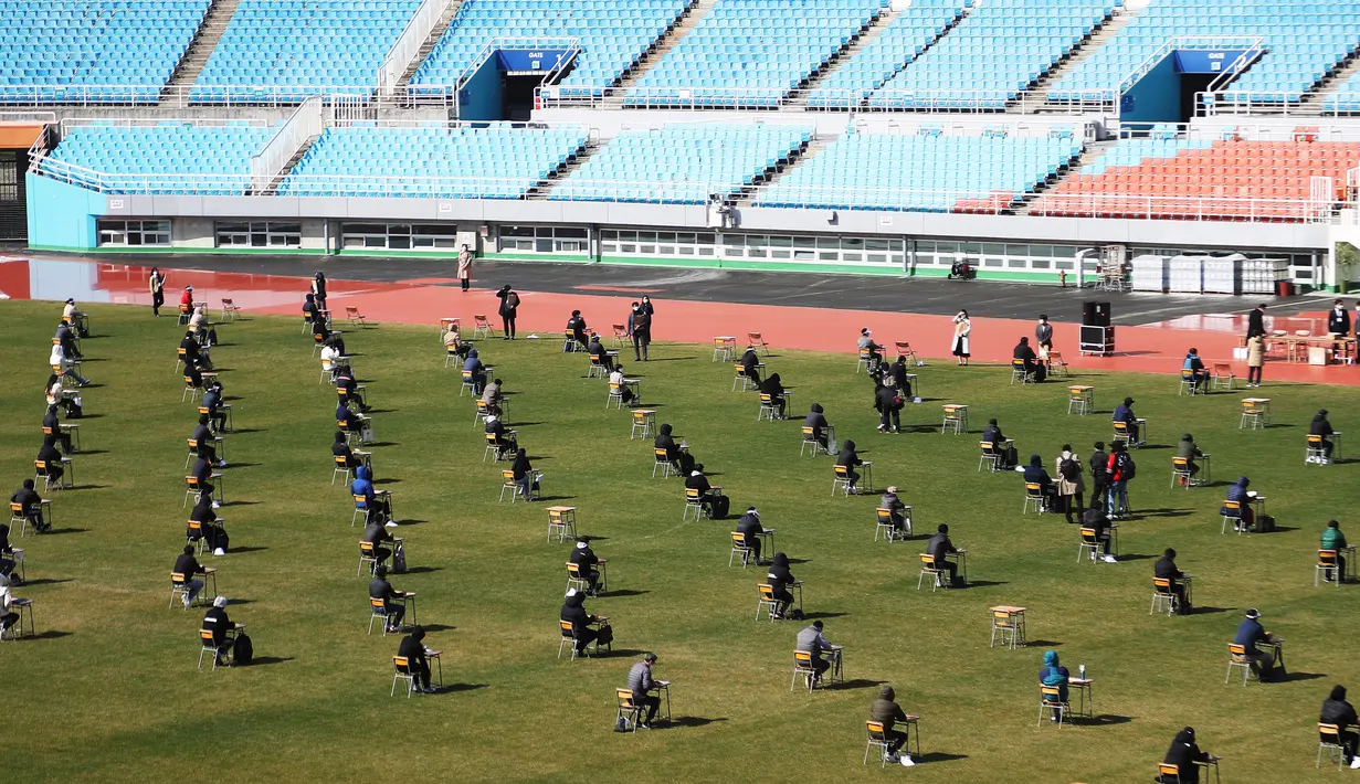 Pelamar kerja saat mengikuti ujian tertulis selama tes rekrutmen untuk Ansan Urban Corporation di stadion Wa di Ansan, Korea Selatan (4/8/2020).  Pelamar juga harus memakai masker wajah dan memeriksa suhunya. (AFP/YONHAP)