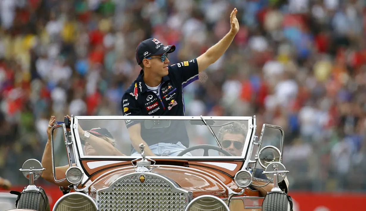 Pembalap Formula Satu dari tim Red Bull, Sebastian Vettel, melambaikan tangan saat berparade mengelilingi Sirkuit Hockenheim menggunakan mobil antik, (20/7/2014). (REUTERS/Kai Pfaffenbach)