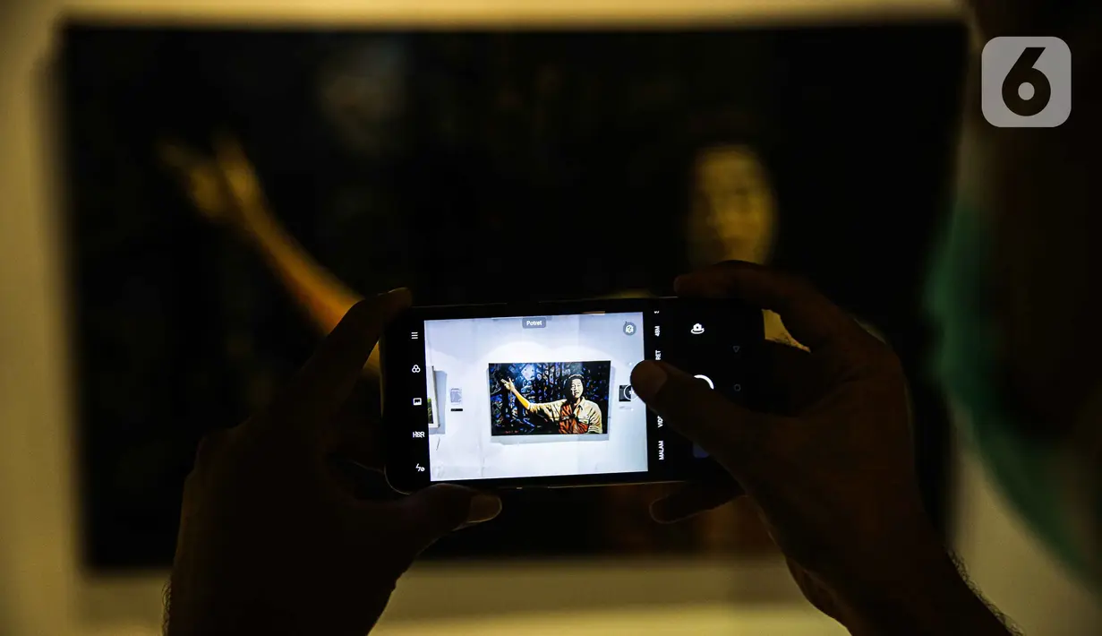 Pengunjung mengambil gambar lukisan yang ditampilkan dalam pameran bertajuk "Hai, Kamu!" di Balai Budaya, Jakarta, Kamis (4/11/2021). Pameran ini akan berlangsung hingga 9 November 2021. (Liputan6.com/Faizal Fanani)